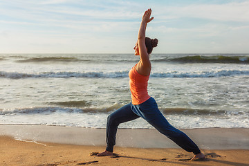 Image showing Woman doing yoga asana Virabhadrasana 1 Warrior Pose on beach on