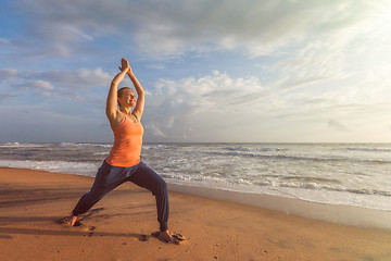 Image showing Woman doing yoga asana Virabhadrasana 1 Warrior Pose on beach on