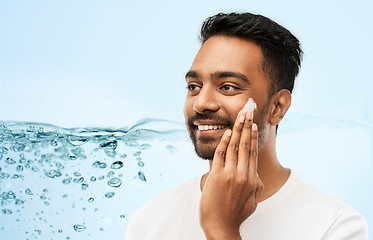 Image showing happy indian man applying cream to face