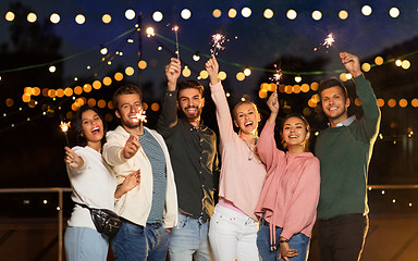 Image showing happy friends with sparklers at rooftop party