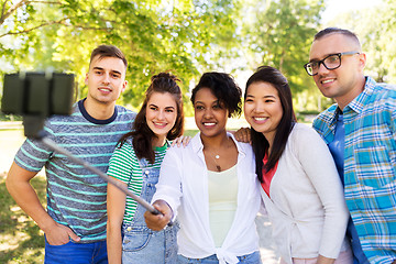 Image showing happy friends taking photo by selfie stick at park