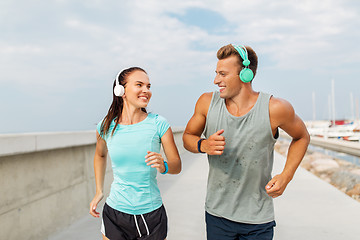 Image showing couple with headphones running outdoors