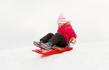 Image showing happy little girl sliding down on sled in winter