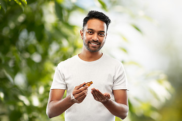 Image showing indian man applying grooming oil to his hand