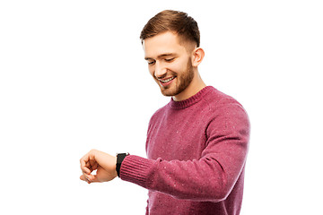 Image showing smiling young man checking time on wristwatch