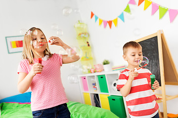 Image showing happy children blowing soap bubbles at home