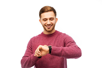 Image showing smiling young man checking time on wristwatch