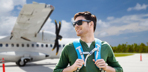 Image showing smiling man with backpack over plane on airfield