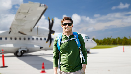 Image showing smiling man with backpack over plane on airfield