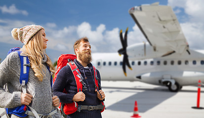 Image showing couple of tourists with backpacks over plane