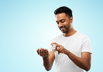 Image showing happy indian man with perfume over blue background