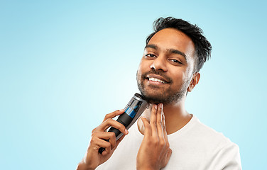 Image showing smiling indian man shaving beard with trimmer