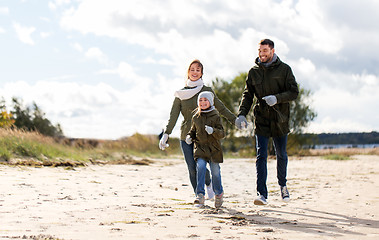 Image showing happy family running along autumn beach