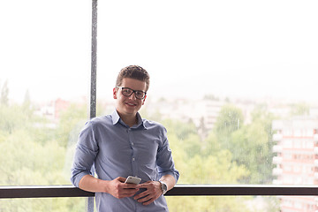 Image showing Businessman Standing In A Modern Building Near The Window With P