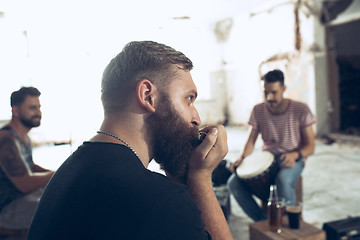 Image showing Repetition of rock music band. man with harmonica and drummer behind the drum set.