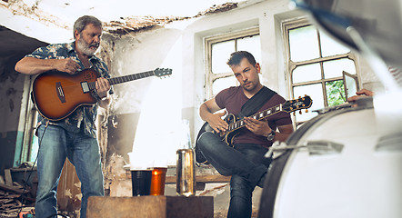 Image showing Repetition of rock music band. Electric guitar player and drummer behind the drum set.