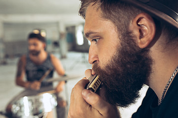 Image showing Repetition of rock music band. man with harmonica and drummer behind the drum set.