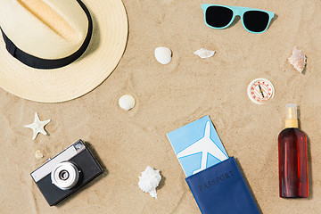 Image showing travel tickets, camera and hat on beach sand