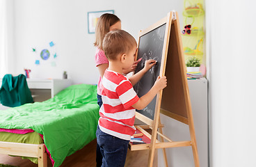 Image showing happy kids drawing on chalk board at home