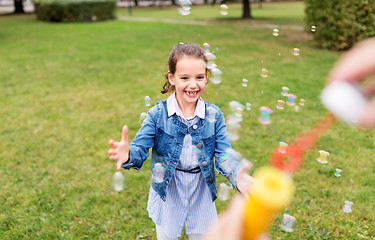 Image showing happy girl playing with soap bubbles at park