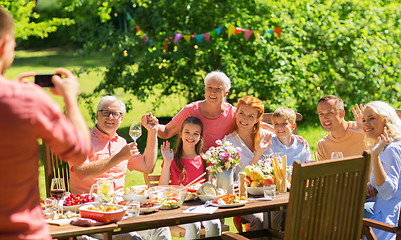 Image showing happy family photographing at dinner in garden