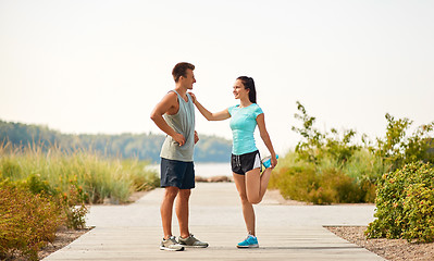 Image showing smiling couple stretching legs on beach