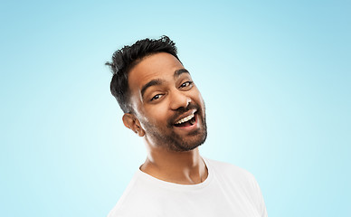 Image showing young laughing indian man over blue background