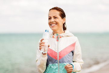 Image showing woman drinking water after exercising on beach