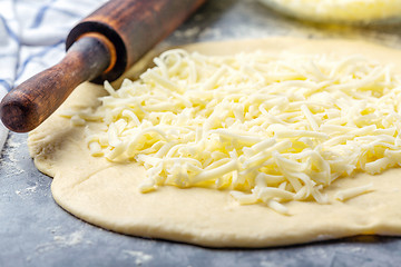 Image showing Grated cheese, rolling pin and dough close-up.