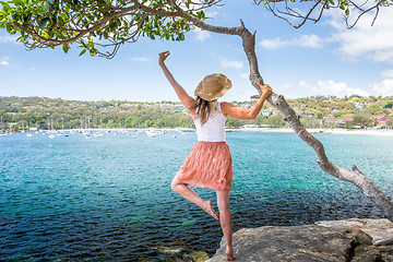 Image showing Happy woman dance pirouette beside tree by the ocean