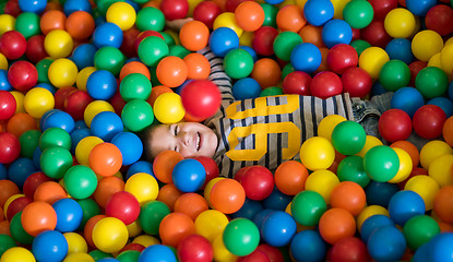 Image showing boy having fun in pool with colorful balls