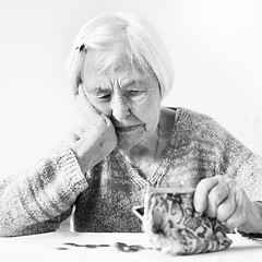 Image showing Elderly woman sitting at the table counting money in her wallet.