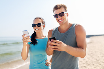 Image showing couple in sports clothes with smartphones on beach