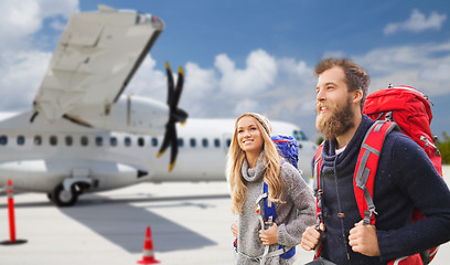 Image showing couple of tourists with backpacks over plane