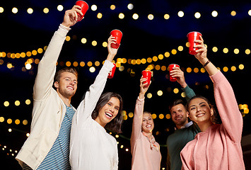 Image showing friends toasting party cups on rooftop at night