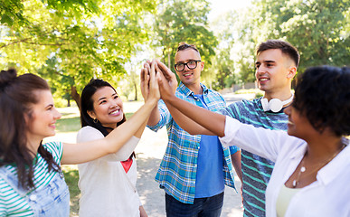 Image showing happy friends making high five in park