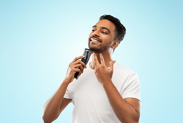 Image showing smiling indian man shaving beard with trimmer