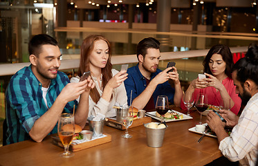 Image showing friends with smartphones at restaurant