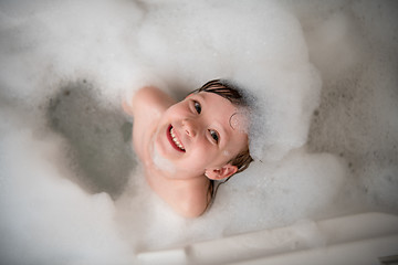 Image showing top view of little girl in bath playing with foam