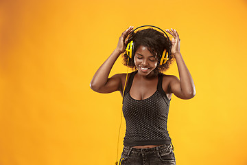 Image showing Studio portrait of adorable curly girl happy smiling during photoshoot. Stunning african woman with light-brown skin relaxing in headphones