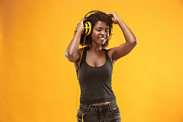 Image showing Studio portrait of adorable curly girl happy smiling during photoshoot. Stunning african woman with light-brown skin relaxing in headphones