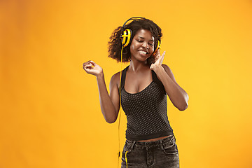 Image showing Studio portrait of adorable curly girl happy smiling during photoshoot. Stunning african woman with light-brown skin relaxing in headphones