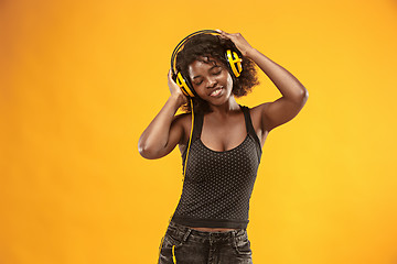 Image showing Studio portrait of adorable curly girl happy smiling during photoshoot. Stunning african woman with light-brown skin relaxing in headphones