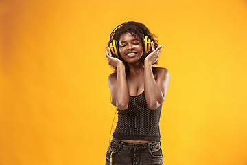 Image showing Studio portrait of adorable curly girl happy smiling during photoshoot. Stunning african woman with light-brown skin relaxing in headphones