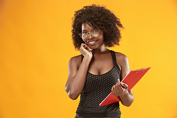 Image showing portrait of a beautiful friendly African American woman with a curly afro hairstyle and red folder