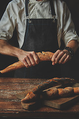 Image showing Male hands break the baguette