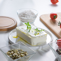 Image showing In a white plate cheese with greens, peeled sunflower seeds and tomatoes on an unused kitchen table