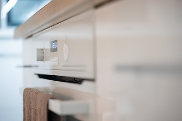 Image showing Modern kitchen surface of new electrical stove with clock indicator and textile towel on it. Photo with shallow depth of field.