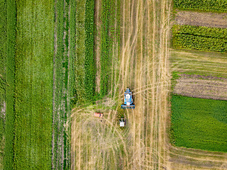 Image showing Agricultural field after harvesting and combine harvester reaps a crop, red car on a field. Aerial view from the drone. Top view