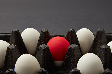 Image showing Closeup of black cardboard box with white and red raw eggs on black background with copy space. Easter concept